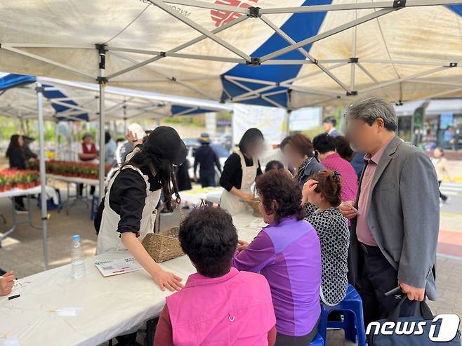 화분 나눔 행사에 참여한 안산 주민들이 세월호와 관련해 이야기꽃을 피우며 추모 메시지를 작성하고 있다. / 뉴스1 박혜연 기자