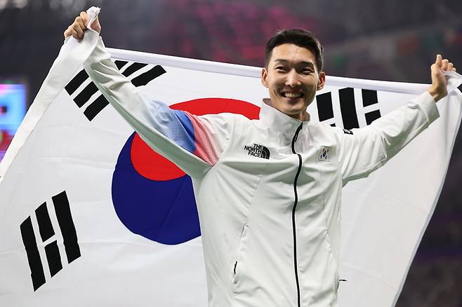 우상혁이 지난해 항저우 아시안게임 남자 높이뛰기 은메달을 차지한 뒤 태극기를 들고 세리머니 하고 있다. 연합뉴스