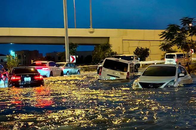 지난 17일(현지시각) 75년 만에 가장 많은 120㎜의 폭우가 쏟아진 아랍에미리트(UAE) 두바이에서 침수된 도로 위를 차량들이 달리고 있다. 두바이/AFP 연합뉴스