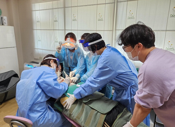 부산의료원 의료진 4명이 중증장애인의 온몸을 붙잡고 치과 치료를 하고 있다.  부산시 제공