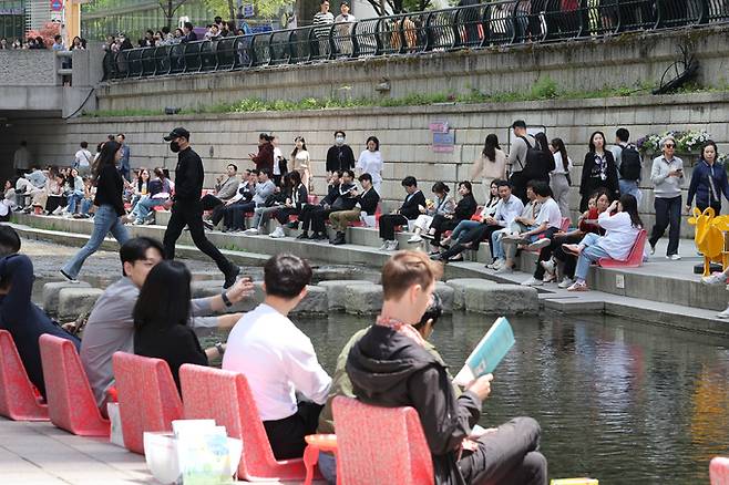 서울지역 낮 최고기온이 25도까지 오르며 초여름 날씨를 보인 18일 오후 서울 중구 청계천을 찾은 시민과 관광객이 물가에 앉아 더위를 식히고 있다. 뉴스1