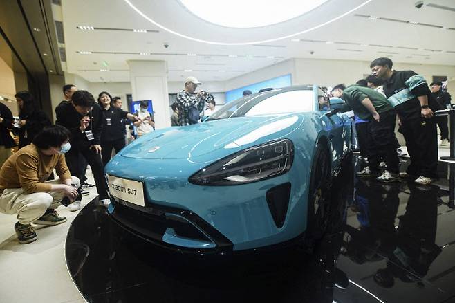 지난달 25일 중국 저장성 항저우의 한 샤오미 매장에서 고객들이 샤오미가 새로 출시한 전기차 SU7을 둘러보고 있다. (사진=AFP)