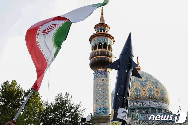 15일(현지시간) 이란 테헤란의 팔레스타인 광장에 사람들이 이란 국기와 미사일 모형을 들고 이스라엘에 대한 공습을 자축하는 모습. 2024.04.15 ⓒ AFP=뉴스1 ⓒ News1 정지윤 기자