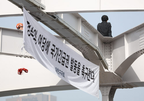신원불명의 남성이 17일 오전 서울 용산구 한강대교 아치 위에 올라가 있다.(사진=연합뉴스)
