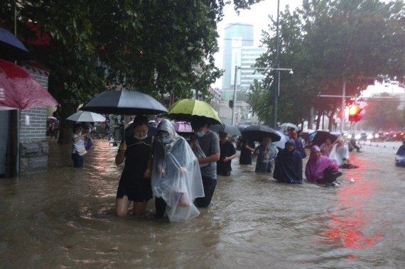 지난 2021년 7월 20일 중국 허난성 정저우에서 시민들이 홍수로 침수된 도심을 지나고 있다.AP뉴시스