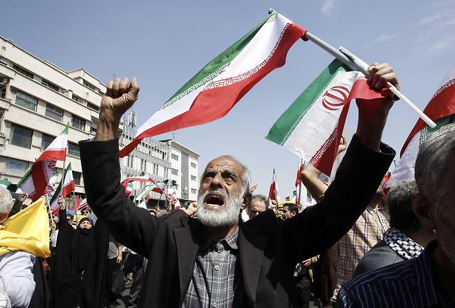19일 이란 테헤란에서 열린 반이스라엘 집회에서 이란인들이 구호를 외치며 이란 국기를 흔들고 있다. [EPA]