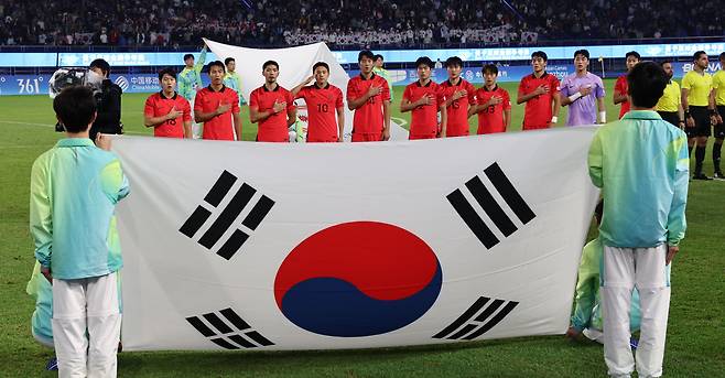 7일 중국 항저우 황룽 스포츠센터 스타디움에서 열린 아시안게임 남자축구 결승전 시작 직전 한국 선수들이 애국가를 부르고 있다. 금메달을 딴 한국 대표팀 가운데 19명이 병역 면제 혜택을 받게 됐다. 거수경례를 하고 있는 현역 군인 조영욱은 조기 제대를 하게 된다. / 연합뉴스