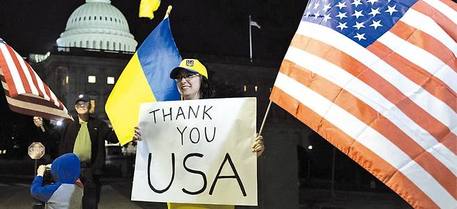 < 우크라 “고맙다, USA” > 미국 상원이 우크라이나 이스라엘 대만 등을 지원하는 안보 패키지 법안을 가결한 23일(현지시간) 우크라이나 지지자들이 미국 워싱턴DC 의회의사당 앞에서 성조기와 우크라이나 국기를 흔들고 있다.  /EPA연합뉴스