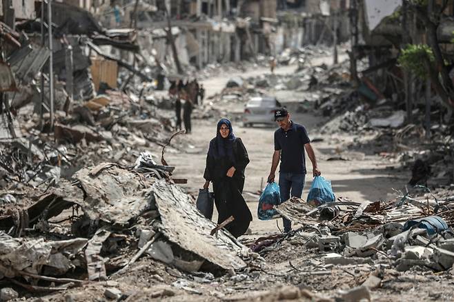 팔레스타인 주민들이 22일(현지시간) 가자지구 남부 칸유니스에서 이스라엘군 공습으로 무너진 건물 사이를 지나가고 있다. AFP연합뉴스