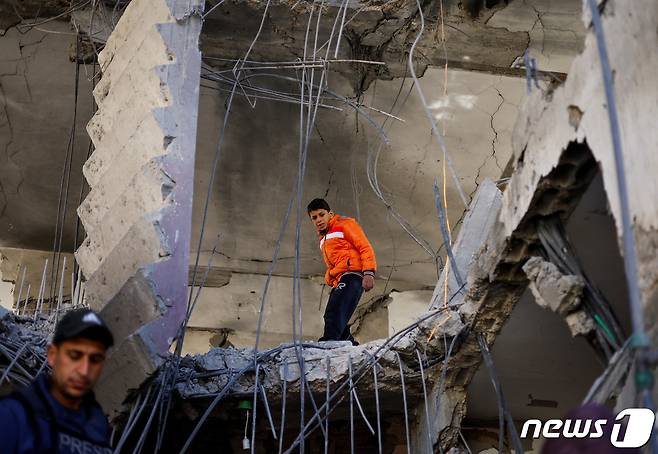 한 팔레스타인 소년이 25일(현지시간) 이스라엘의 공습으로 무너진 가자지구 라파의 한 건물 안에서 돌아다니고 있다. 2024.03.25 ⓒ 로이터=뉴스1 ⓒ News1 정지윤 기자