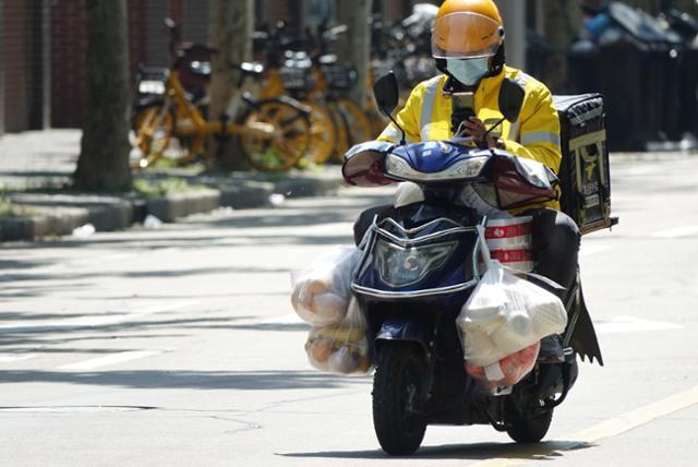 중국 상하이의 한 거리에서 배달 기사가 주문 음식이 주렁주렁 달린 오토바이를 타고 배달하고 있다. 상하이=연합뉴스