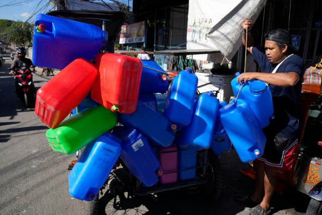 기온이 섭씨 40도를 웃돌던 이달 2일 필리핀 마닐라 케손에서 한 시민이 빈 물통을 자전거에 묶고 있다. 마닐라=AP 연합뉴스