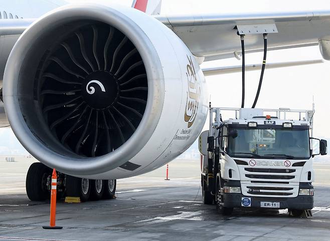 에미레이트항공 보잉 777-300ER 한 대가 2023년 1월 30일 아랍에미리트(UAE) 두바이 공항에서 엔진을 작동시킨 가운데 연료 트럭이 지속 가능한 항공 연료(SAF)를 채우는 시범을 보이고 있다. /로이터