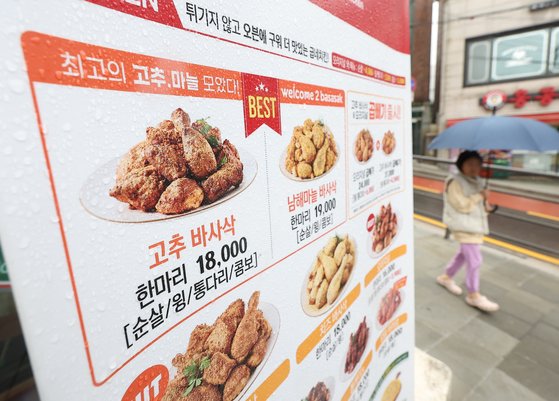 서울 시내 한 굽네치킨 매장 앞에 인상 이전 가격 안내판이 놓여 있다. 연합뉴스