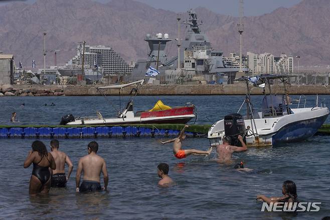[에일랏=AP/뉴시스] 4월16일 이스라엘 최남단 홍해 도시 에일랏 해변에서 주민들이 이스라엘 해군의 최신 Saar-6 코르벳함을 배경으로 해수욕을 즐기고 있다. 예멘 후티 반군의 공격이 이어지면서 이스라엘 군함들이 이 해역을 순찰하고 있다. 2024.04. 26.