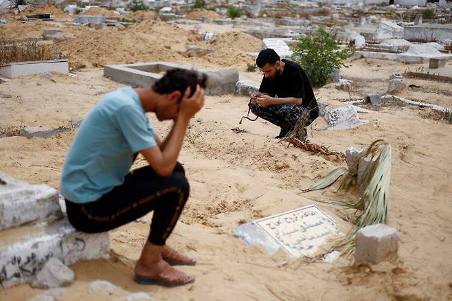 26일 이스라엘군 공습으로 치명상을 입은 어머니에게서 극적으로 태어났다 숨진 아기의 삼촌인 라미 알셰이크가 가자 남부 라파에 위치한 가족들의 무덤 옆에 쪼그려 앉아 있다. (사진=로이터 통신)