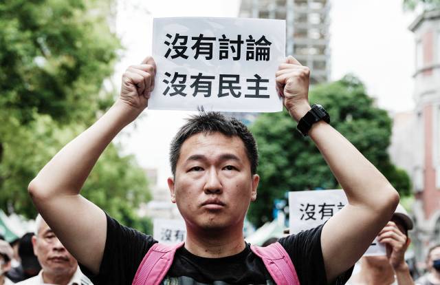 대만 야권이 입법원(국회)의 권한을 확대하고 정부 견제 기능을 강화하는 내용의 의회 개혁법안 처리를 추진하는 가운데 이에 반대하는 시위 참가자가 21일 타이베이 입법원 앞에서 ‘토론 없이는 민주주의도 없다’고 적힌 피켓을 들고 있다. 지난 17일 입법원에선 이 법안 처리를 놓고 여야 의원들이 난투극을 벌였다. AFP연합뉴스