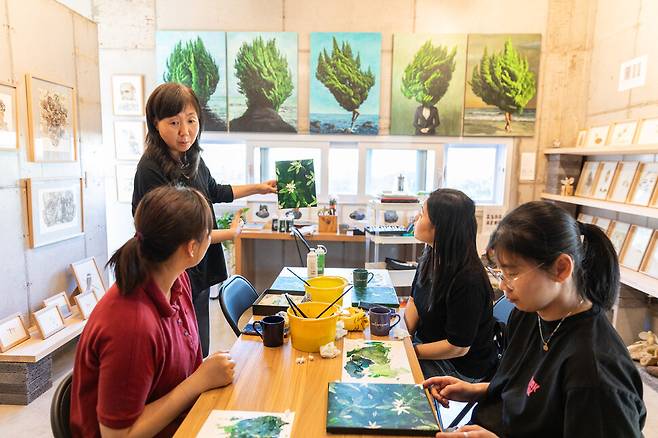 신효마을의 화실 ‘그림휴가’에서 김미형 대표(맨 오른쪽)가 체험객들에게 귤꽃 그림이 담긴 아크릴화를 설명하고 있다. 이수현 제공