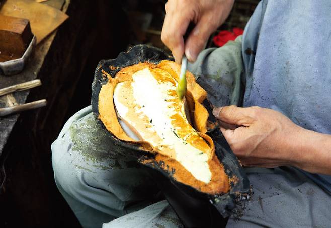 수작업으로 구두 형틀에 가죽을 접착하고 있다.