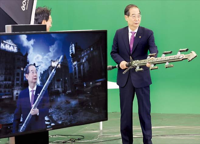 한덕수 국무총리가 18일 경기 성남시 판교 네오위즈를 방문해 ‘P의 거짓’ 게임 속 아이템을 들고 크로마키 촬영 체험을 하고 있다. 연합뉴스