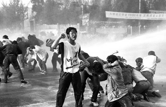 1991년 4월27일 서울 연세대학교에서 열린 ‘강경대 학우 살인 규탄대회’를 마치고 교문을 나선 학생들이 경찰의 물대포 세례를 맞으며 ‘살인정권 타도’ 구호를 외치고 있다. 명지대생 강경대는 전날 등록금 인상 반대 시위에 참여했다가 ‘백골단’이라 불리던 사복경찰의 쇠파이프에 맞아 죽었다. 한겨레 자료사진