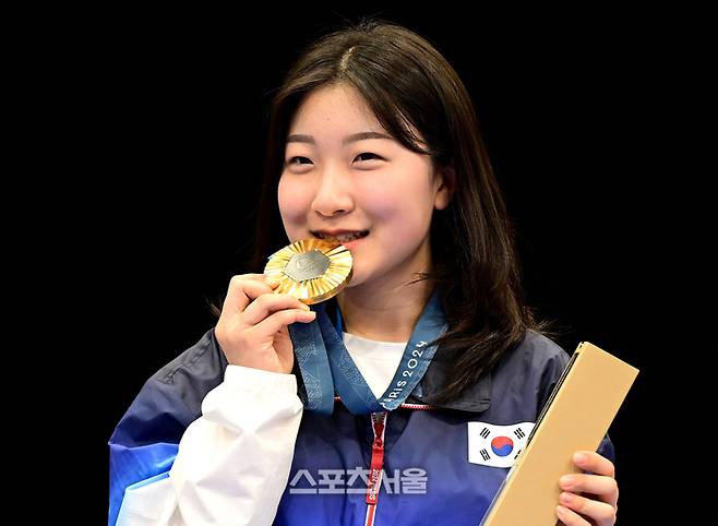 사격 국가대표 반효진이 29일(한국시간)?프랑스 샤토루 슈팅센터에서 열린?2024 파리올림픽 공기소총 10m 여자 개인전에서 황위팅(중국)과 접전을 벌이며 올림픽 신기록으로 1위를 차지한 뒤 시상대 위에서 금메달을 물어보이며 기념촬영을 하고 있다. 2024. 7. 29. 샤토루 | 박진업 기자 upandup@sportsseoul.com