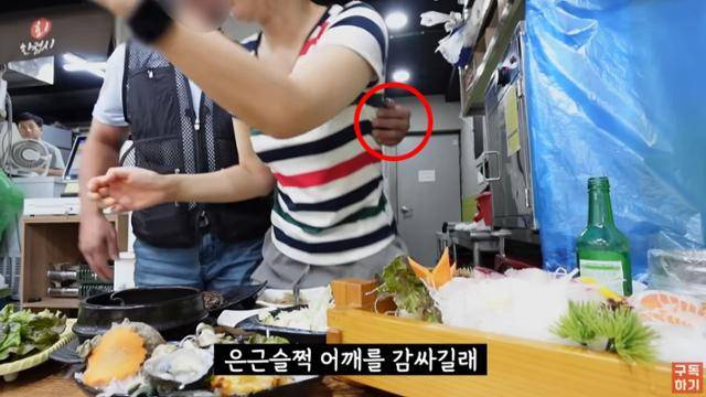 먹방 유튜버 윤숙희가 먹방을 찍던 도중 한 남성이 다가와 사진 촬영을 요구한 뒤 윤숙희의 몸을 감싸고 있다. 유튜브 캡처