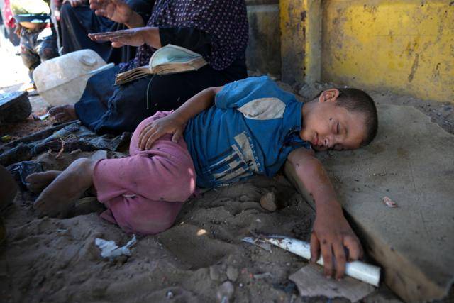 지난달 20일(현지시간) 가자지구 데이르 알발라 서쪽 해변에서 한 팔레스타인 난민 어린이가 텐트촌 그늘에 누워 잠을 청하고 있다. 데이르 알발라=AP 뉴시스