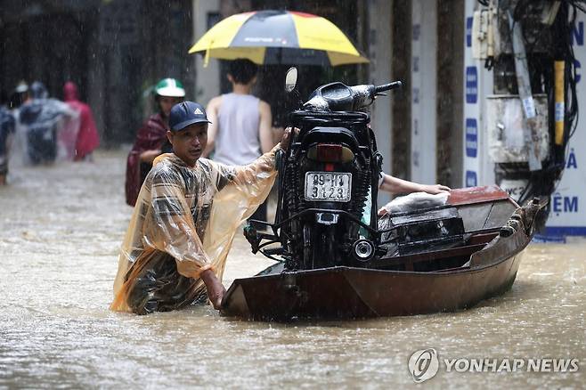 물에 잠긴 하노이 (하노이 EPA=연합뉴스) 11일(현지시간) 베트남 수도 하노이에서 침수된 지역의 한 주민이 오토바이를 보트에 실어 나르고 있다. 2024.09.11