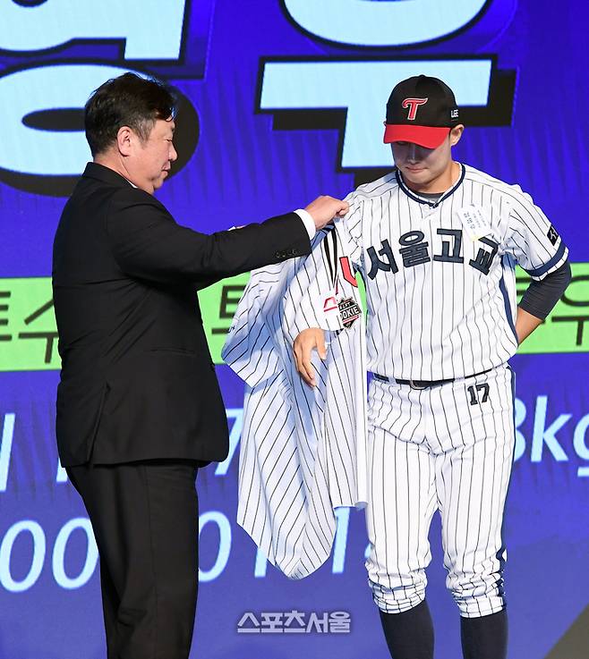 서울고 투수 김영우(오른쪽)가 11일 서울 송파구 롯데호텔 월드 크리스탈 볼룸에서 열린 ‘2025 KBO 신인 드래프트’에서 전체 10순위로 LG에 지명된 뒤 차명석 단장의 도움을 받아 유니폼을 입고 있다. 2024. 9. 11. 박진업 기자 upandup@sportsseoul.com