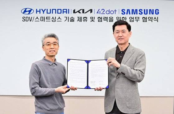25일 삼성전자와 현대자동차그룹이 삼성전자 서울 R&D캠퍼스에서 기술제휴 업무 협약식을 맺었다. 송창현 현대차?기아 AVP본부 사장(왼쪽)과 전경훈 삼성전자 DX부문 최고기술책임자(CTO) 겸 삼성리서치장 사장(오른쪽)이 기념 사진을 촬영하고 있다. 사진 삼성전자