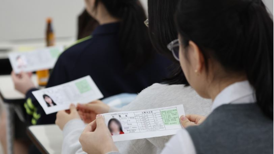2025학년도 대학수학능력시험을 하루 앞둔 13일 오전 부산 금정구 동래여고에서 수험생이 수험표와 음료수를 받아 들고 있다. (사진=연합뉴스)