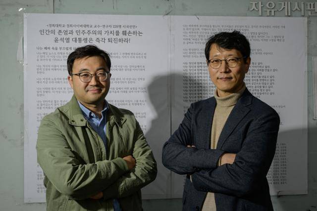 화제가 된 경희대 시국선언문을 작성한 장문석(왼쪽) 국문과 교수와 김진해 후마니타스칼리지 교수가 지난 25일 시국선언문이 게시된 경희대 문과대 게시판 앞에서 포즈를 취했다. 하상윤 기자
