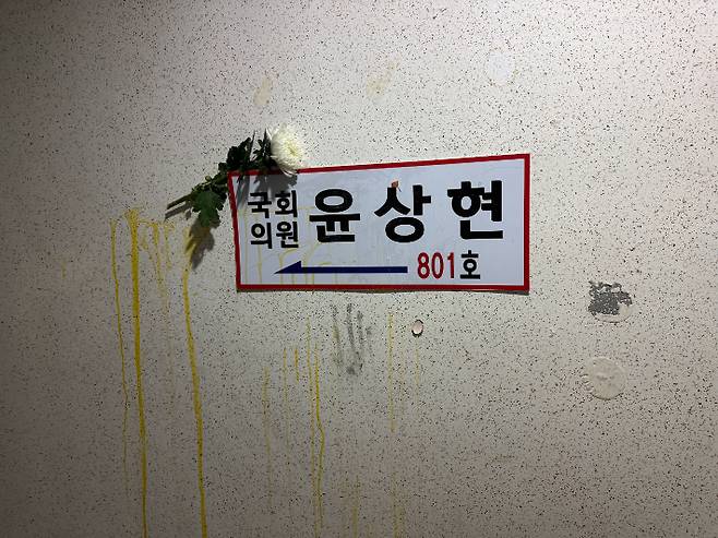9일 인천 미추홀구 국민의힘 윤상현 의원 사무실 입구 벽 간판에 계란 투척 흔적과 흰 국화가 걸려 있는 모습. 독자 제공