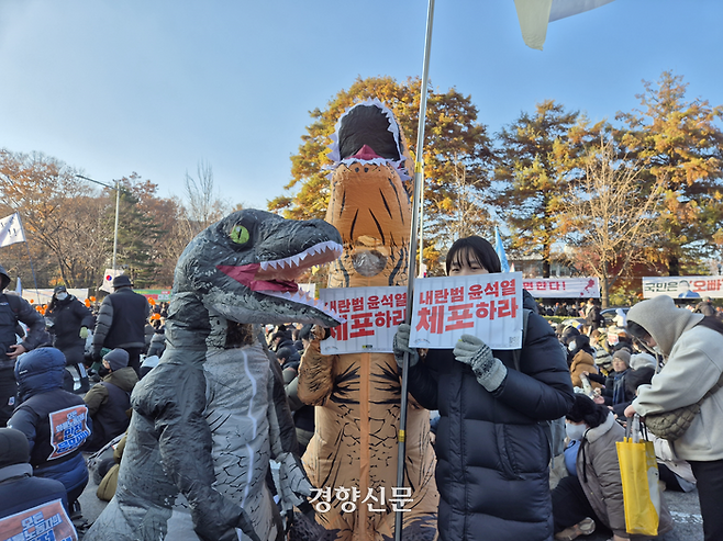 한소현씨와 친구들이 14일 서울 영등포구 여의도에서 열린 윤 대통령 퇴진 시민촛불에 공룡 옷을 입고, ‘중생대 공룡협회’ 깃발을 들고 참석했다. 이예슬 기자