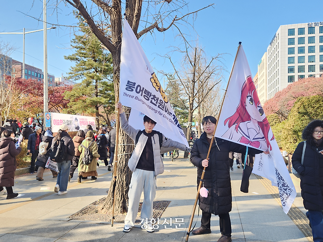대학생 황보현씨(왼쪽)와 직장인 김도균씨가 14일 서울 영등포구 여의도에서 열린 윤석열 대통령 퇴진 시민 촛불에 ‘붕어빵 3개에 천원 연합’ 깃발과 애니메이션 캐릭터가 그려진 깃발을 들고 참석했다. 김정화 기자