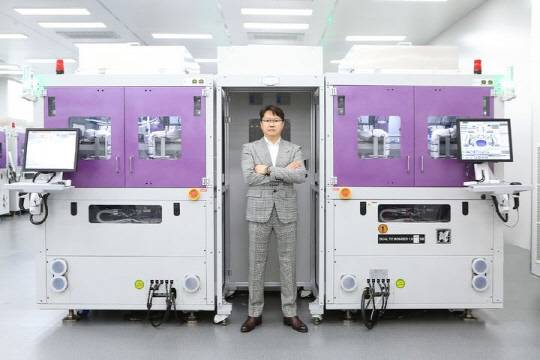 곽동신 한미반도체 회장이 HBM 제조용 TC본더 장비 앞에서 포즈를 취하고 있다. <한미반도체 제공>