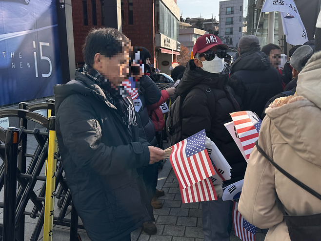A pro-Yoon protester distributes miniature American and South Korean flags, emphasizing that their display symbolizes the Korea-US alliance and inspires a sense of strength among demonstrators. (Moon Joon-hyun/The Korea Herald)