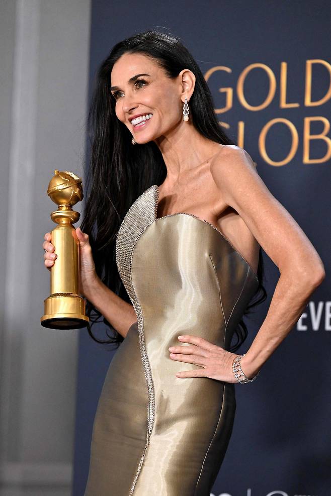 배우 데미 무어가 5일(현지 시각) 제82회 골든글로브 시상식에서 연기 인생 47년 만에 처음 받은 연기상 트로피를 들고 웃고 있다. 무어가 이날 입은 드레스는 아르마니 프리베에서 특별 제작했다. /AFP 연합뉴스