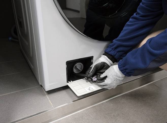 삼성전자 서비스 엔지니어가 세탁기 잔수 호스에 남은 물을 배출하고 있다./사진=삼성전자서비스