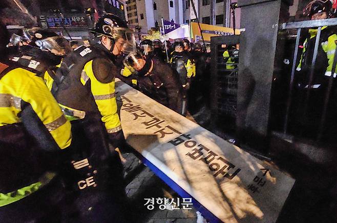 19일 새벽 서울서부지법 후문에서 윤석열 대통령 구속에 항의하며 법원 청사를 침입해 난동을 부린 시위대가 넘어뜨린 법원 간판을 경찰이 일으키고 있다. 이준헌 기자