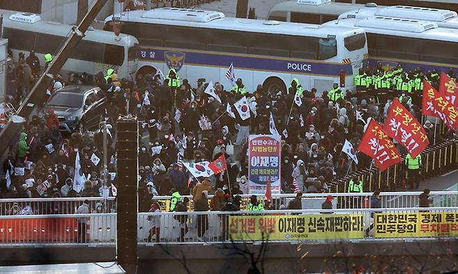 지난 15일 서울 용산구 한남동 대통령 관저 입구 앞에서 윤 대통령 지지자들이 태극기를 흔들고 있다. 연합뉴스