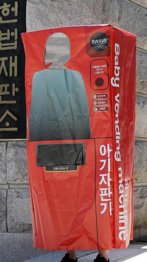 여성을 생산의 도구라고 여기는 시선에 대한 저항으로 한 여성이 "아기자판기"라고 쓰인 코스튬을 입고 시위하고 있다