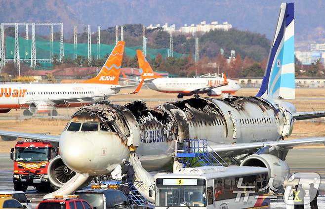 지난달 28일 부산 강서구 김해국제공항에서 이륙을 준비하던 홍콩행 에어부산 항공기 BX391편 내부에서 불이 나 승객과 승무원 등이 비상 탈출한 가운데 29일 불에 탄 에어부산 항공기 뒤로 제주항공 여객기가 오가는 모습. 28일 밤 항공기 화재 사고 당시 승객 170명(탑승 정비사 1명 포함)과 승무원 6명은 비상 슬라이드를 통해 전원 탈출했다. 2025.1.29/뉴스1 ⓒ News1 윤일지 기자