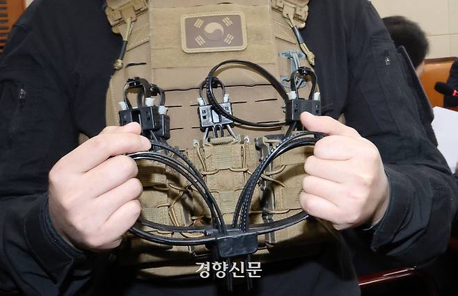 박선원 더불어민주당 의원 보좌직원이 20일 국회 국방위 전체회의에서 707 특임단의 흑복을 입고 당시 소지했던 체포용 케이블타이보여 주고 있다. 김현태 707특임단장은 플라스틱 수갑이 국회 문 봉쇄용이라고 주쟝했다. 박민규 선임기자