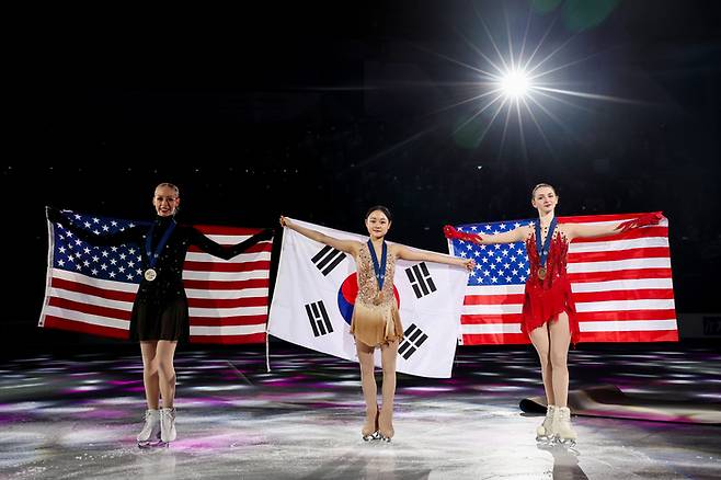23일 서울 목동 아이스링크에서 열린 2025 국제빙상경기연맹(ISU) 사대륙 피겨 선수권대회 여자 싱글 프리스케이팅에서 금메달을 획득한 김채연(가운데)이 태극기를 펼쳐 들고 포즈를 취하고 있다. 왼쪽부터 은메달 미국 브레이디 테넬, 김채연, 동메달 미국 사라 에버하트. 연합뉴스