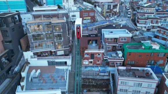 부산 동구 초량동 168계단 옆에 다음 달부터 운행을 시작할 경사형 엘리베이터(가운데 초록 레일)가 설치돼 있다. (부산 동구청 제공)