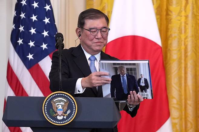 이시바 시게루 일본 총리가 2월 7일 워싱턴 백악관에서 열린 공동 기자회견에서 도널드 트럼프 대통령이 선물한 사진집을 들어 보이고 있다./AP 연합뉴스