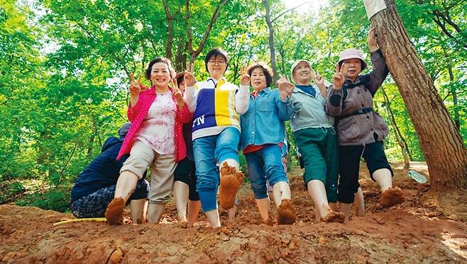 이순희 강북구청장이 ‘북한산 체험형 숲속쉼터’에서 주민들과 함께 황토밭에서 발 마사지를 하고 있다. 강북구 제공