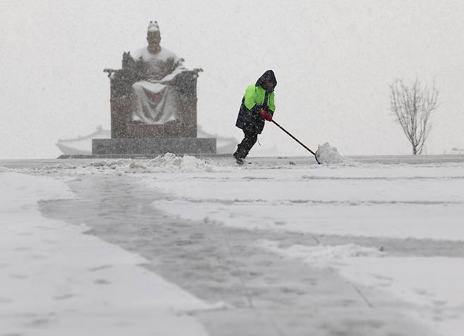 눈이 내린 18일 서울 종로구 광화문광장에서 한 관계자가 눈을 치우고 있다. 연합뉴스